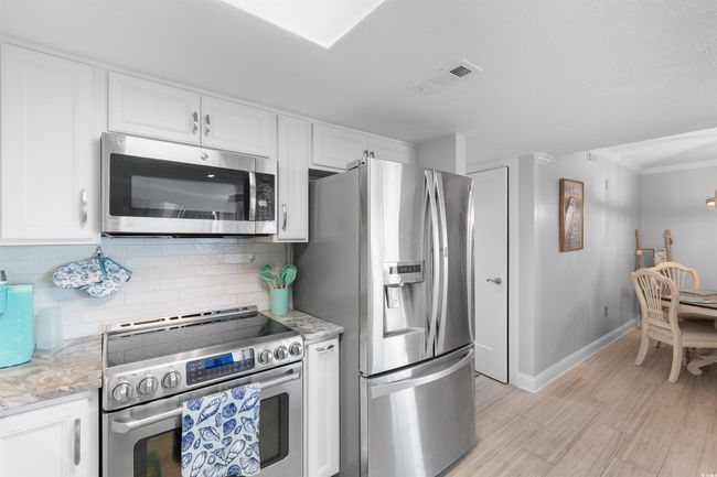 Kitchen with stainless steel appliances, white cabinets, baseboards, backsplash, and crown molding | Image 5