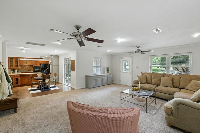 Living area with ceiling fan, crown molding, and light carpet | Image 18