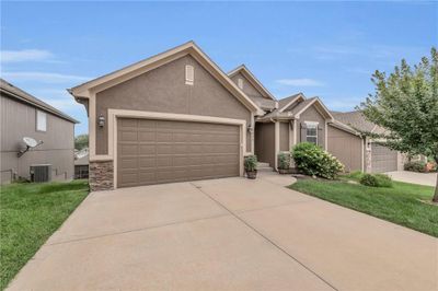 View of front of home featuring a front lawn, a garage, and cooling unit | Image 1