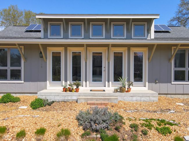exterior space featuring solar panels, board and batten siding, and a shingled roof | Image 4