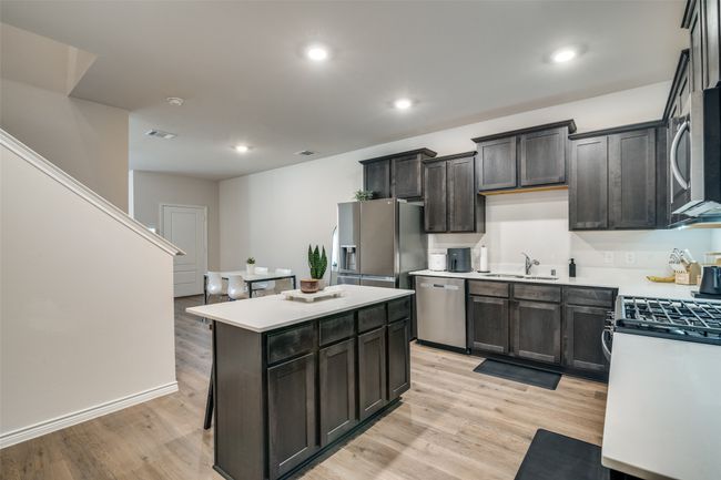 Kitchen with appliances with stainless steel finishes, light countertops, a kitchen island, light wood-type flooring, and recessed lighting | Image 14