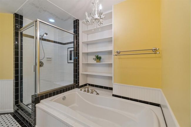 Bathroom with a bath, a shower stall, a chandelier, wainscoting, and tile patterned floors | Image 20