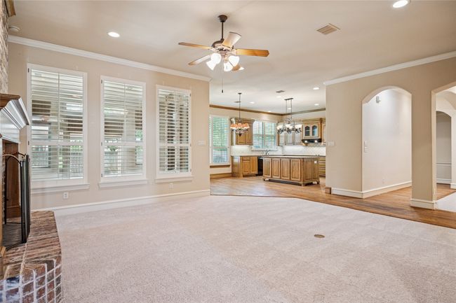 Living room with plantation shutters, new carpet, ceiling fan, crown molding, recessed lighting, and arched walkways. | Image 5