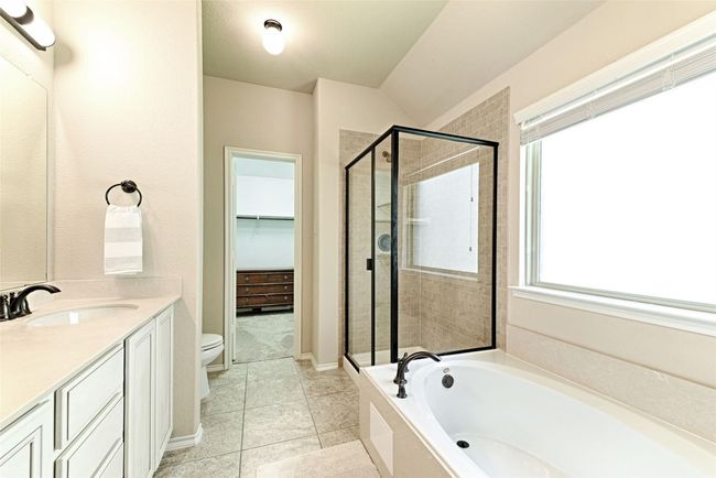 Full bath featuring a stall shower, a bath, vanity, a spacious closet, and tile patterned floors | Image 14