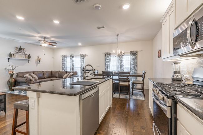 Kitchen with dark wood finished floors, visible vents, appliances with stainless steel finishes, a sink, and dark countertops | Image 9