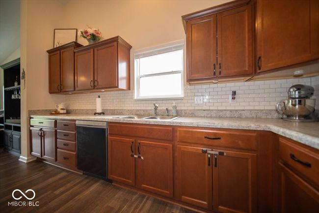 kitchen featuring dishwasher, a sink, dark wood-style flooring, decorative backsplash, and light countertops | Image 14