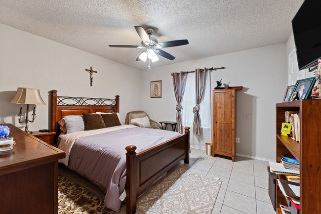 Bedroom featuring a textured ceiling, light tile patterned flooring, and a ceiling fan | Image 13