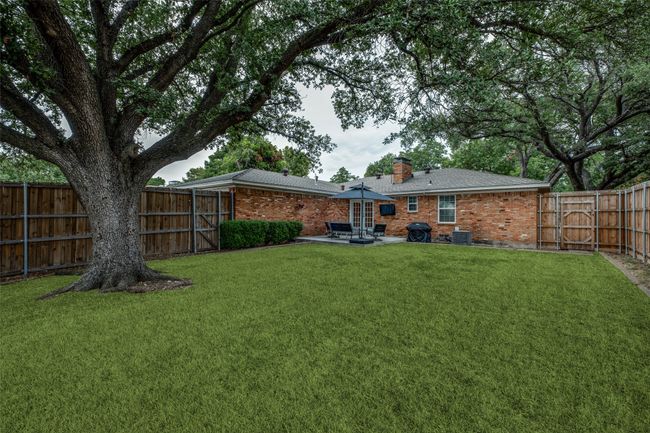 Rear view of house featuring a patio, brick siding, a chimney, a fenced backyard, and a gate | Image 35