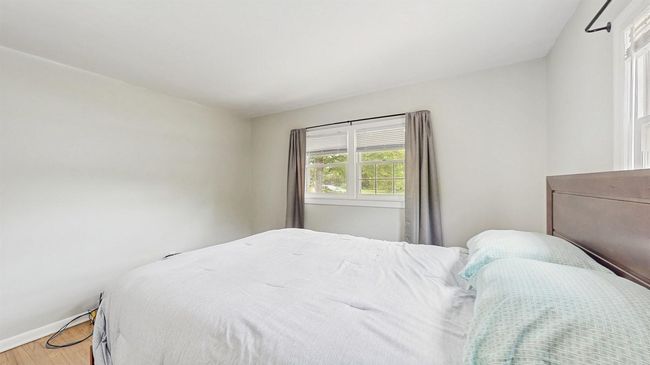 Bedroom featuring light stained hardwood flooring and baseboard heating units. | Image 22