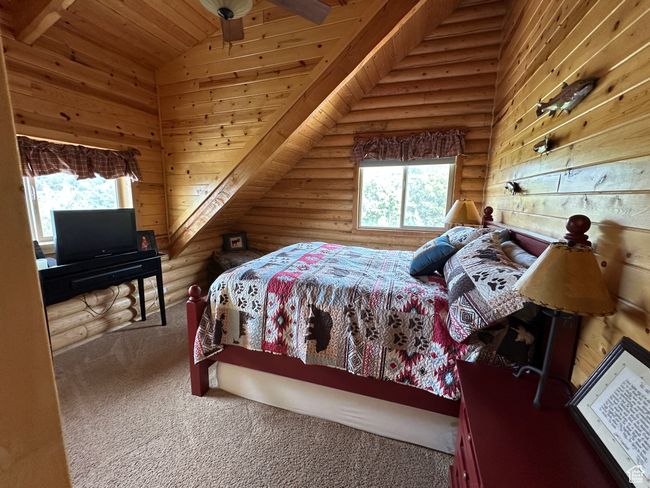 Carpeted bedroom with log walls, lofted ceiling, multiple windows, and wood ceiling | Image 14