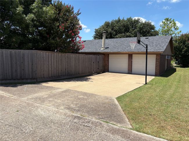 View of home's exterior featuring roof with shingles, brick siding, driveway, and a garage | Image 14