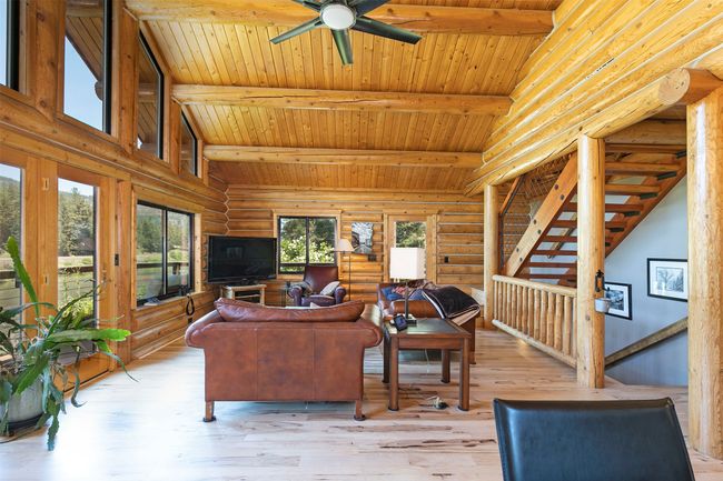 Living room with rustic walls, wooden ceiling, light wood-style floors, and ceiling fan | Image 7