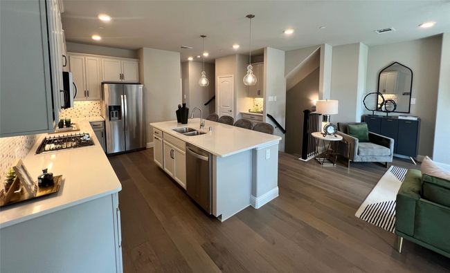 Kitchen with open floor plan, appliances with stainless steel finishes, light countertops, dark wood finished floors, and decorative backsplash | Image 4