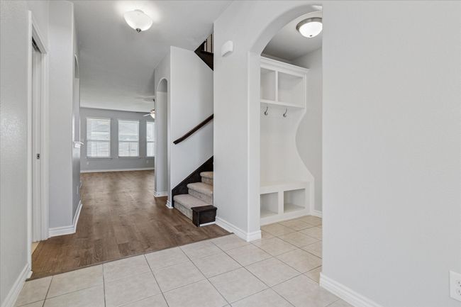 Mudroom featuring light tile patterned floors, arched walkways, baseboards, and ceiling fan | Image 7