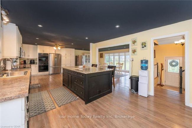 Kitchen featuring appliances with stainless steel finishes, sink, white cabinets, light hardwood / wood-style floors, and a kitchen island | Image 17