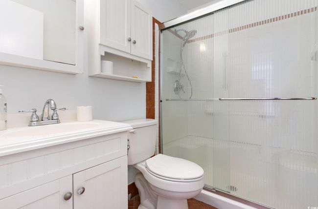 Bathroom featuring vanity, toilet, and a shower with door | Image 21