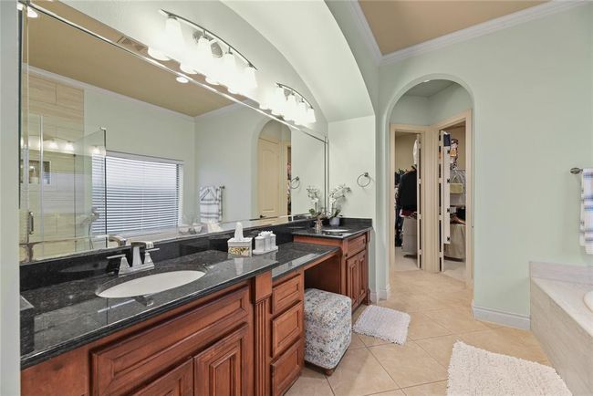 Primary bathroom adorned with arches over the double sinks, vanity and doorway to the twin walk in closets. | Image 17