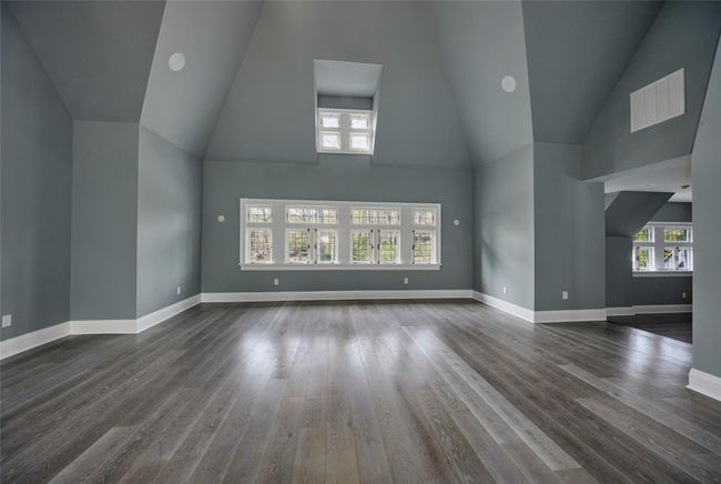 Unfurnished living room with visible vents, high vaulted ceiling, wood finished floors, and baseboards | Image 12