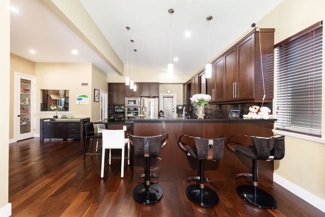 Kitchen featuring appliances with stainless steel finishes, a peninsula, dark wood-style flooring, dark brown cabinetry, and recessed lighting | Image 14