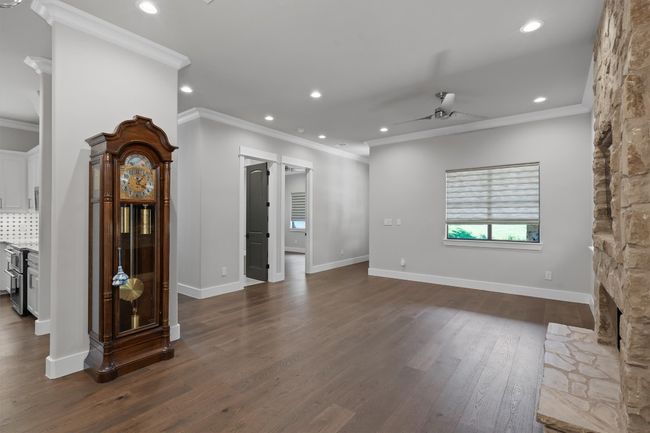 Unfurnished living room featuring a ceiling fan, dark wood-style flooring, and ornamental molding | Image 5