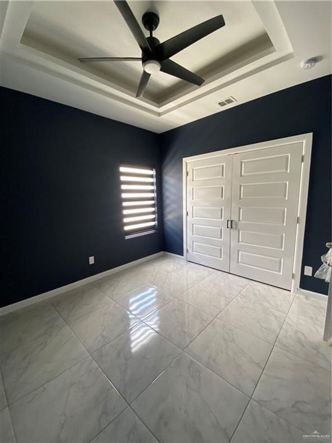Unfurnished bedroom with a tray ceiling, light marble finish floors, a ceiling fan, and a closet | Image 12