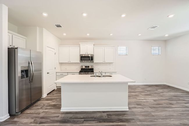 Kitchen with a sink, an island with sink, visible vents, and stainless steel appliances | Image 11