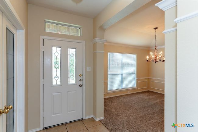 Front entry way showing the front door and formal dining room with new carpet, large window and light fixture. | Image 4