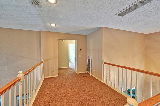 The loft offers a versatile space with warm carpeting, ample natural light, and a cozy ambiance—perfect for a home office or reading nook. | Image 26