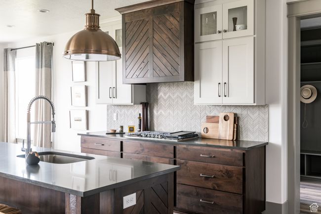 Kitchen featuring stainless steel gas stovetop, sink, dark brown cabinets, and white cabinets | Image 5