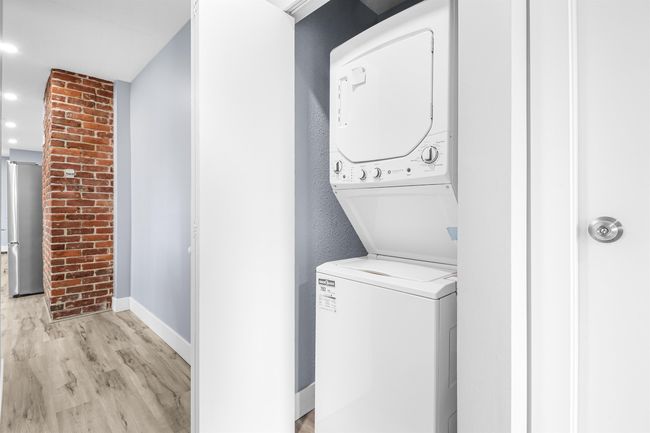 Clothes washing area featuring baseboards, stacked washer / drying machine, laundry area, and light wood-style floors | Image 15