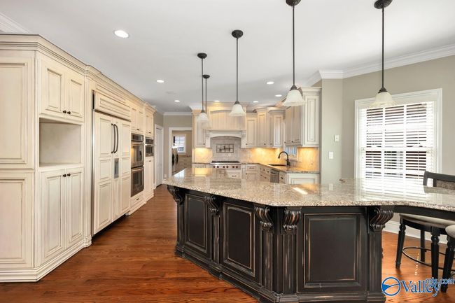 Wood flooring, wood cabinetry, kitchen island with bar seating, recessed lighting | Image 12