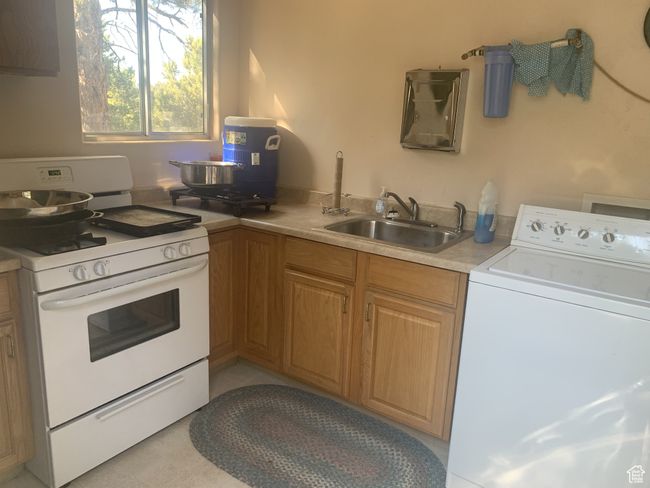 Kitchen featuring washer / clothes dryer, a sink, white gas range oven, and light countertops | Image 25