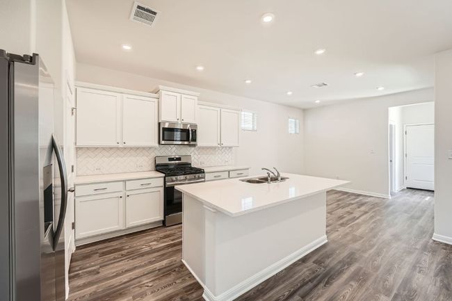 Kitchen featuring a sink, stainless steel appliances, dark wood-type flooring, white cabinets, and backsplash | Image 10