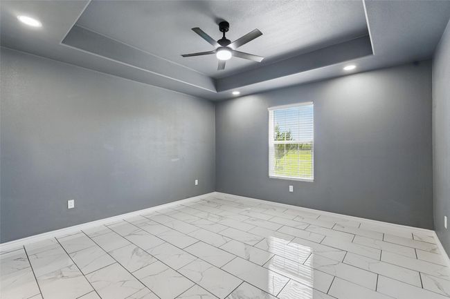 Spare room with ceiling fan, baseboards, marble finish floor, and a raised ceiling | Image 12