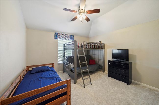 Cozy bedroom with neutral walls and carpet, featuring a ceiling fan and a window for natural light. The room includes a closet with double doors, offering ample storage space. | Image 25