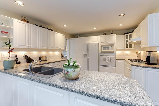 Kitchen featuring tasteful backsplash, glass insert cabinets, white cabinetry, a sink, and white appliances | Image 13