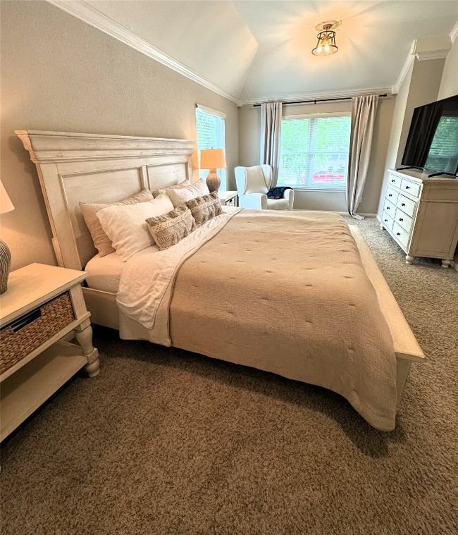 Primary Bedroom featuring vaulted ceiling, light colored carpet, and ornamental molding. | Image 30