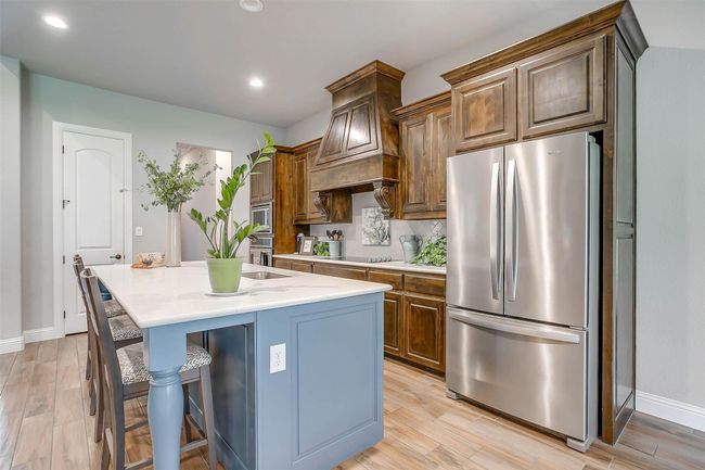 Kitchen featuring stainless steel appliances, a kitchen island with sink, light countertops, light wood-style flooring, and recessed lighting | Image 14