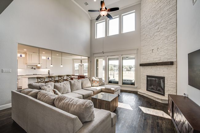 Living room featuring a stone fireplace, a high ceiling, dark hardwood / wood-style floors, and ceiling fan | Image 8