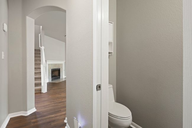 Bathroom with baseboards, wood finished floors, toilet, a tile fireplace, and a textured wall | Image 14