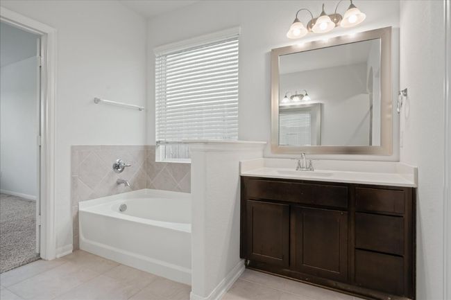 Primary Bathroom featuring a garden tub, vanity, tile patterned flooring, and baseboards | Image 25