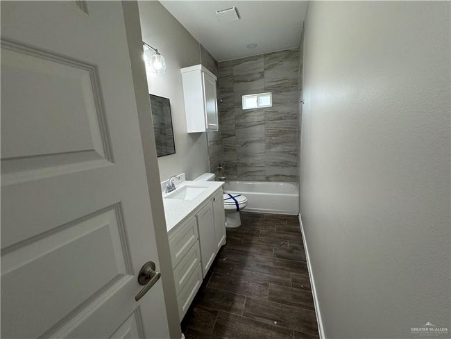 Bathroom featuring vanity, toilet, washtub / shower combination, wood finished floors, and baseboards | Image 18
