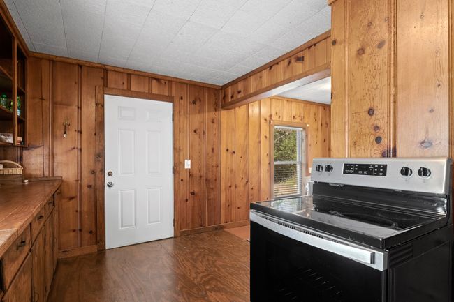 Kitchen with dark hardwood / wood-style flooring, wooden walls, and stainless steel electric range oven | Image 15