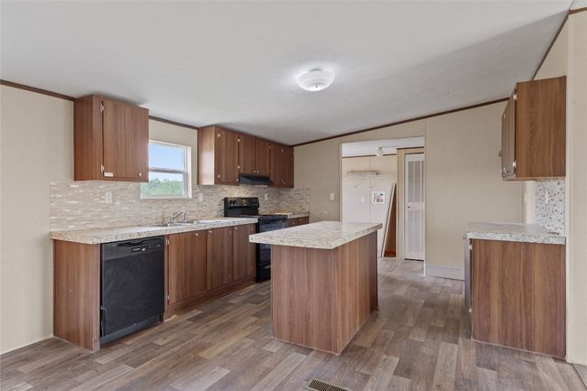 Kitchen featuring black appliances, tasteful backsplash, dark wood-style flooring, light countertops, and under cabinet range hood | Image 13