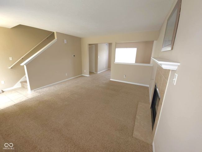 unfurnished living room featuring baseboards, stairs, carpet, and a fireplace | Image 12