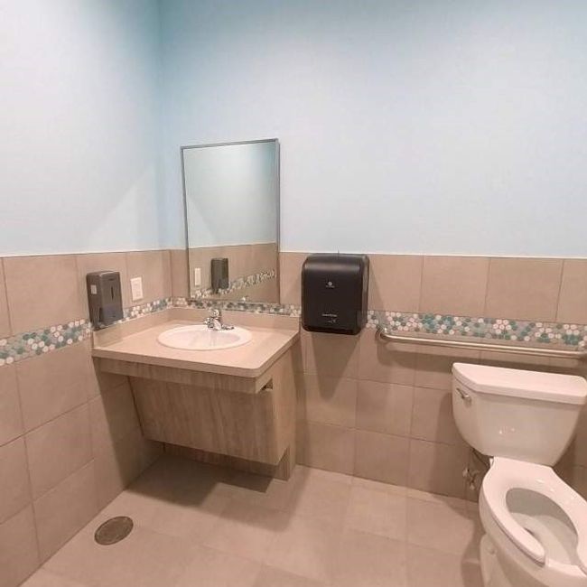 Bathroom featuring tile walls, toilet, wainscoting, vanity, and tile patterned floors | Image 12