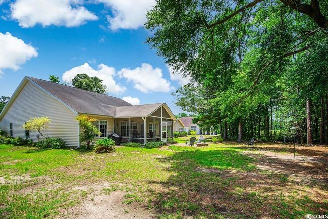 Rear view of house featuring a sunroom, a fire pit, and a lawn | Image 29