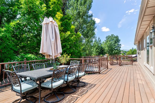 Wooden deck featuring outdoor dining area and view of scattered trees | Image 47