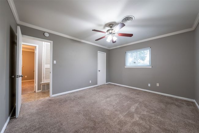 Carpeted empty room featuring ornamental molding, ceiling fan, and a smoke detector | Image 20