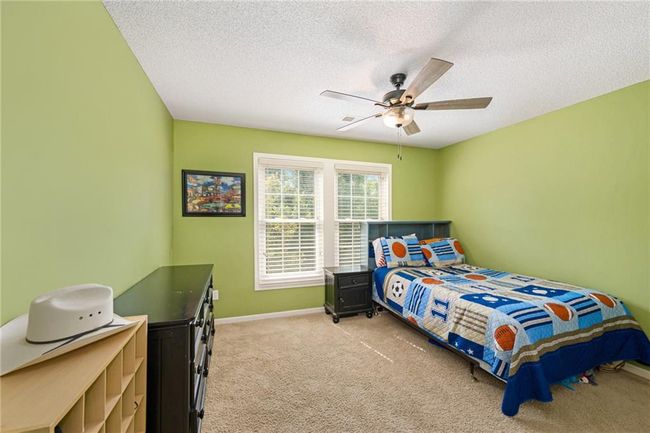 Bedroom featuring light colored carpet, a textured ceiling, baseboards, and a ceiling fan | Image 21